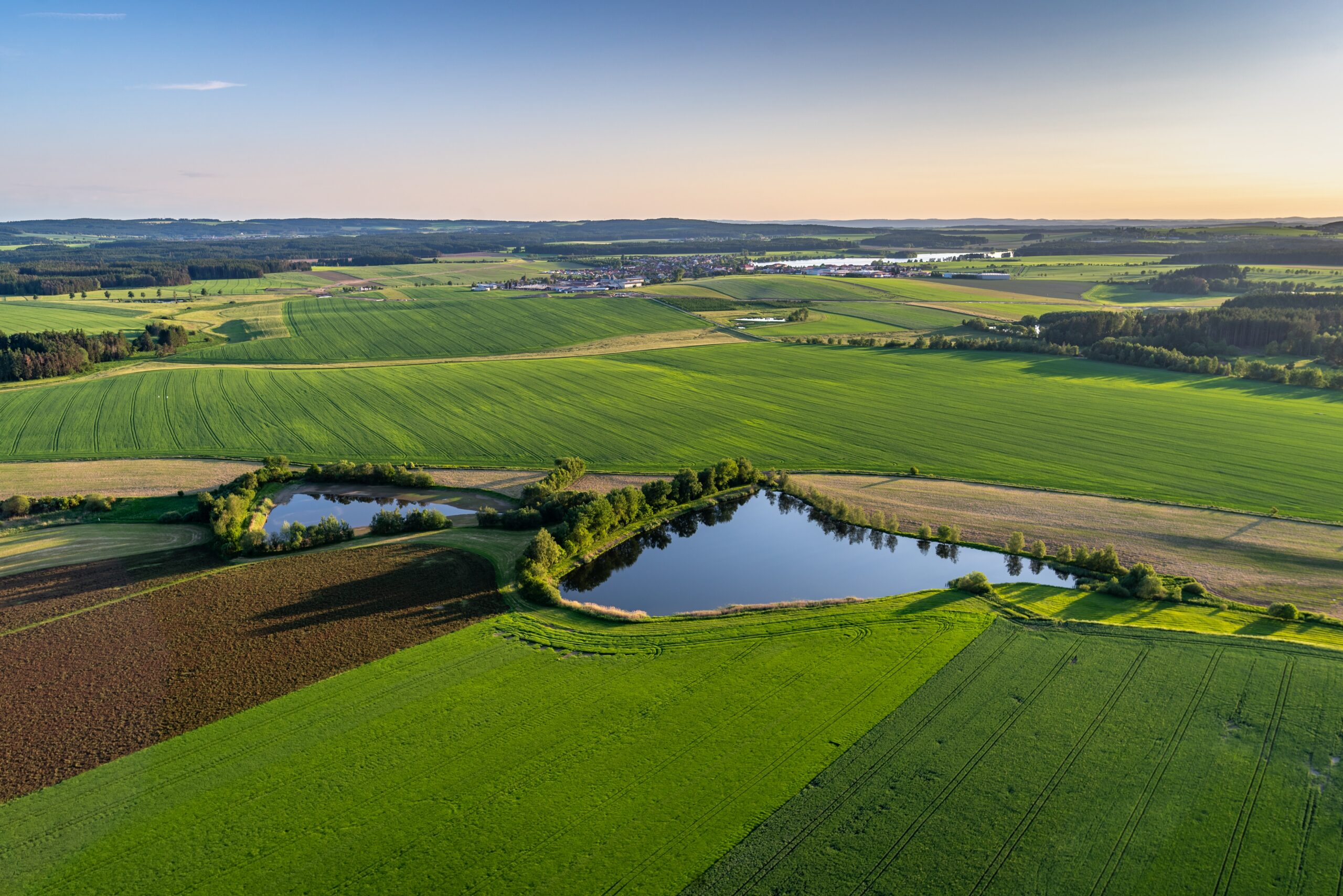 A bird's-eye shot of breathtaking green fields with small ponds in a rural area. Perfect for rural scenarios.